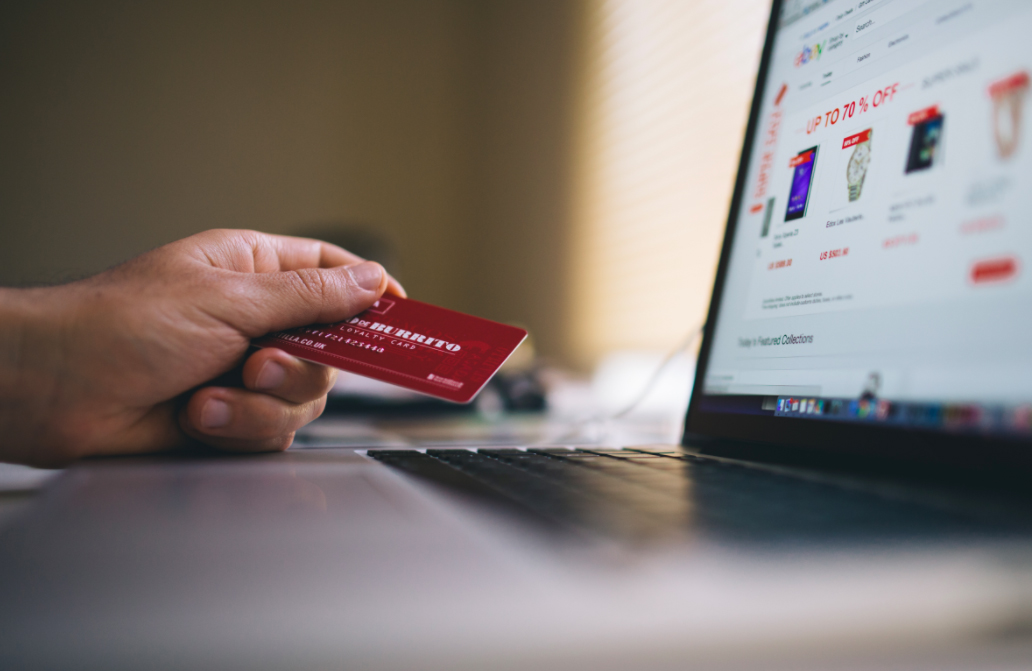 A person holding a branded loyalty card whilst browsing on a laptop.
